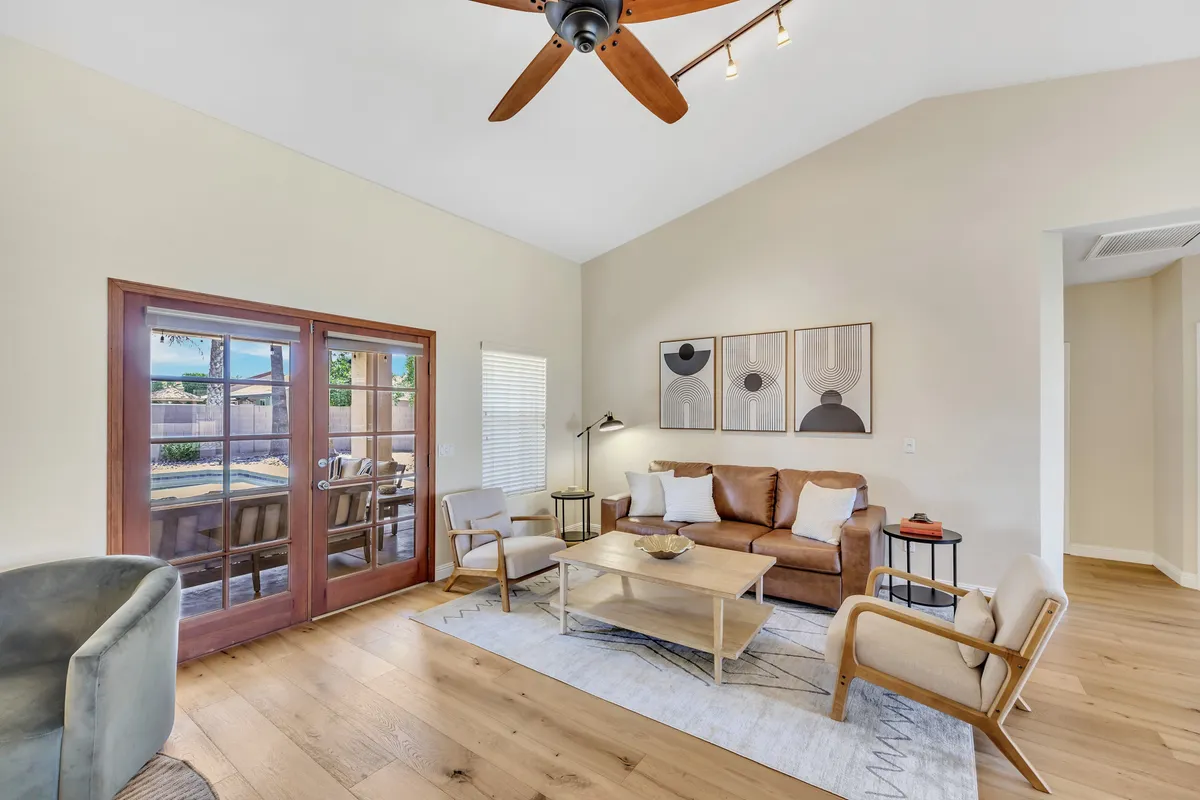 A spacious, open-concept living room with comfortable sofas, tasteful artwork, and French doors that let in natural light. The arrangement promotes conversation and relaxation, making it ideal for collaborative work sessions or team downtime.
