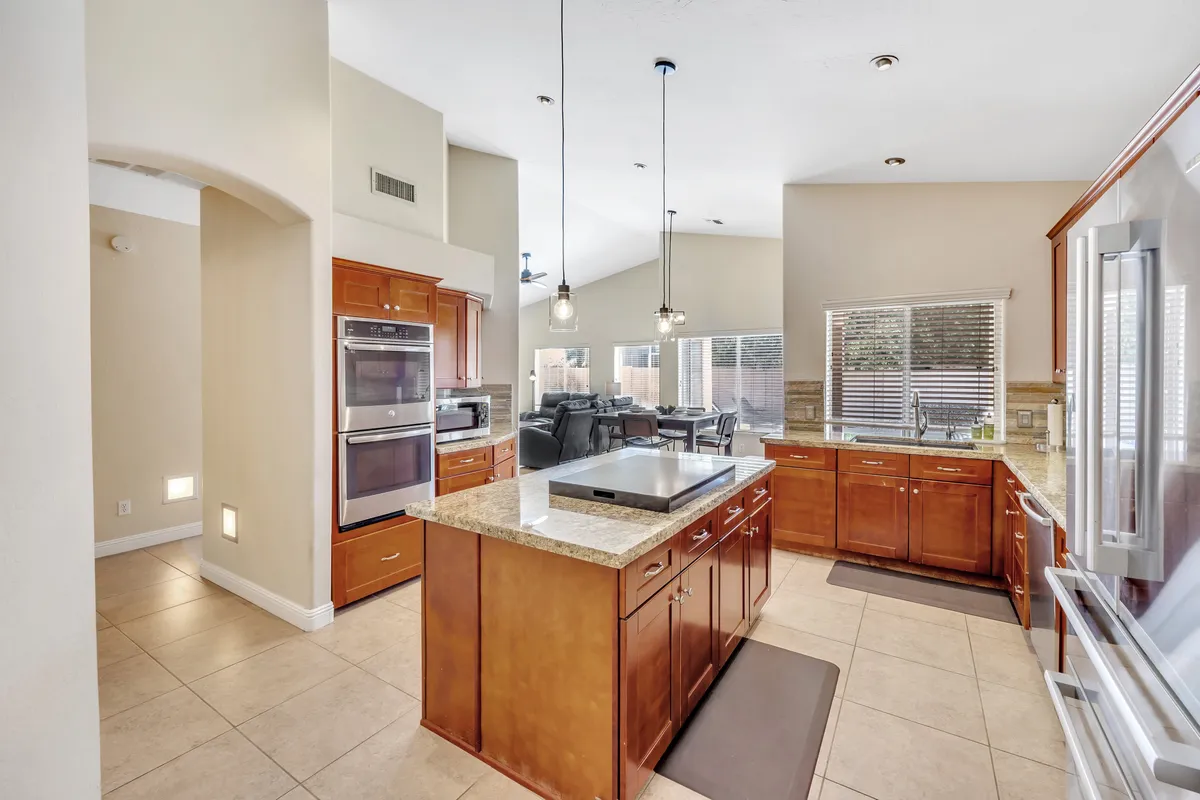 This image showcases a central island with a granite countertop, surrounded by modern appliances and wood cabinetry. The spacious layout is ideal for cooking and entertaining, with plenty of room for family gatherings or casual dining.