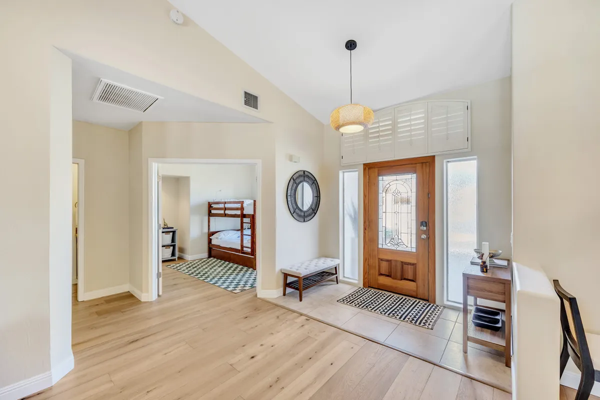 An inviting entryway featuring a front door, a welcoming bench, a mirror, and tasteful décor. Natural light and a well-organized space create a warm first impression, suggesting easy transitions between indoor comfort and outdoor adventures.