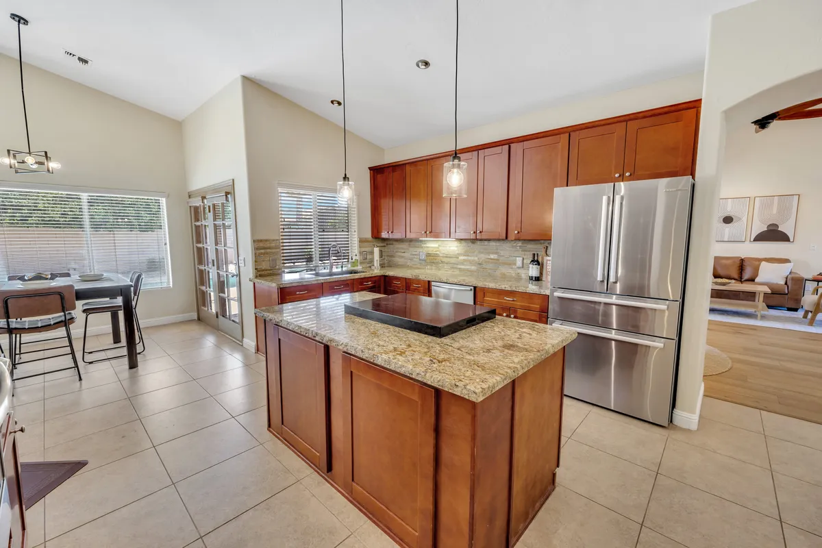Features a kitchen with granite countertops, wood cabinetry, stainless steel appliances, and pendant lighting, providing a warm and welcoming environment for cooking and entertaining.