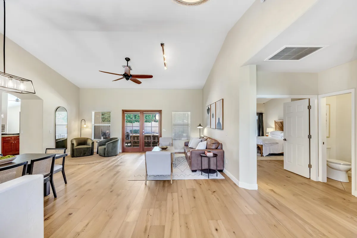 A spacious open-concept living area seamlessly connecting a comfortable lounge with a dining space. Large windows allow sunlight to pour in, highlighting cozy seating and tasteful artwork, encouraging both relaxation and social interaction.