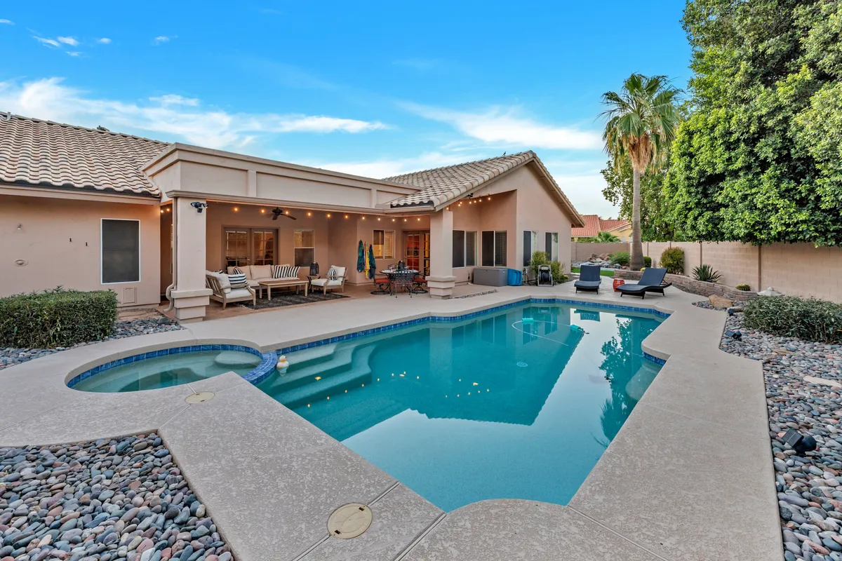 A spacious backyard featuring a crystal-clear swimming pool, outdoor seating area, and lush landscaped garden. The space is perfectly suited for morning coffee by the water, afternoon sunbathing, or evening barbecues with friends under the stars.