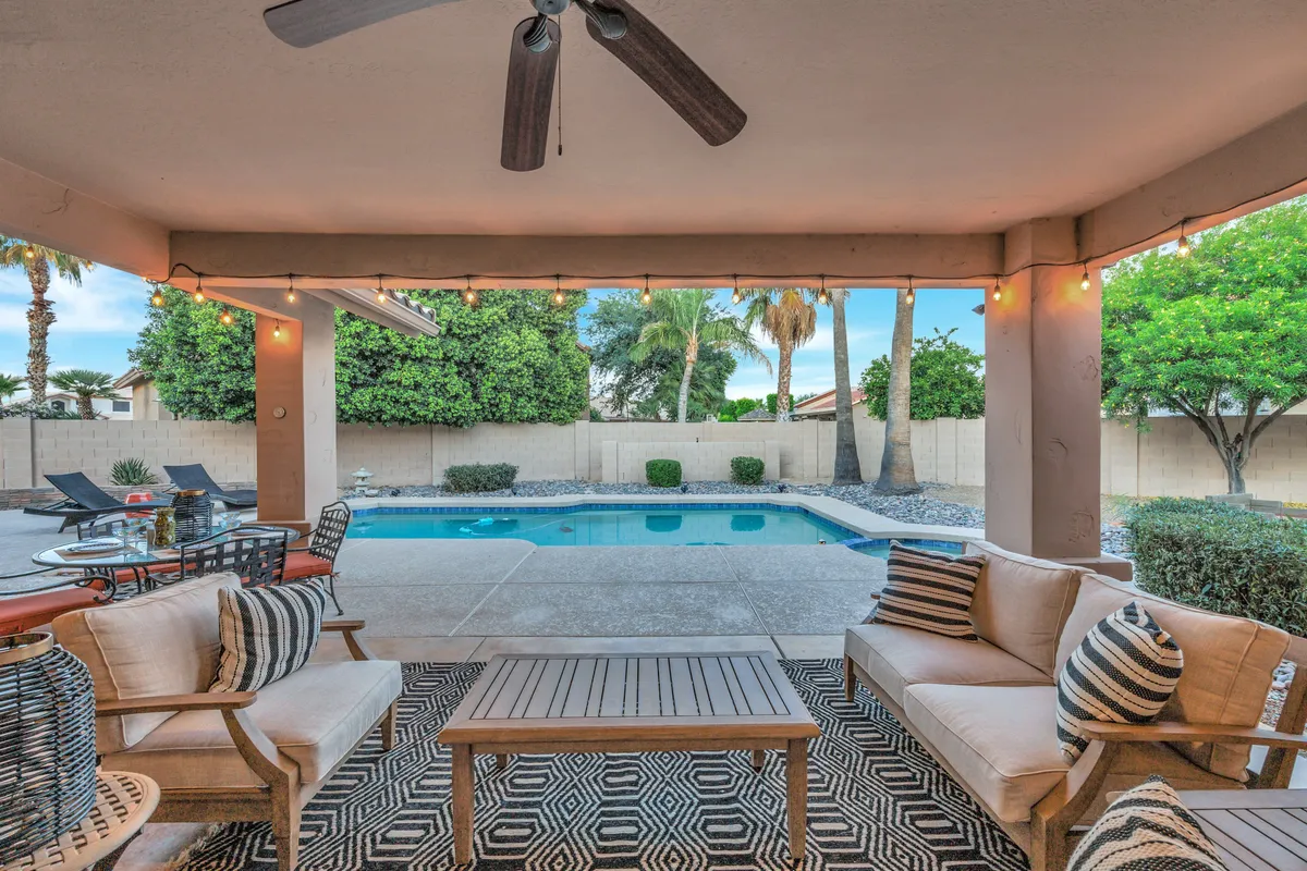 An inviting exterior scene with a serene seating area beside the pool, surrounded by well-maintained desert landscaping. The setup invites residents to relax, socialize, or stargaze in a peaceful environment—showcasing the tranquil atmosphere of the neighborhood.